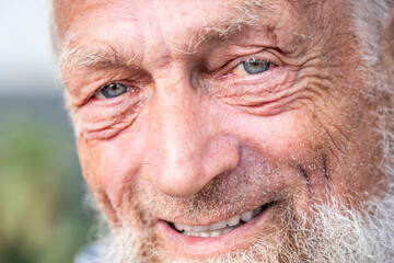 Close up portrait of happy 70-year-old optimist man with smiling wrinkled face, a touch of sadness...