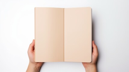 Fototapeta premium hands holding an open notebook with blank beige pages against a white background