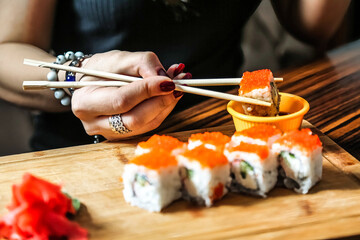 Woman Holding Chopsticks Over a Plate of Sushi
