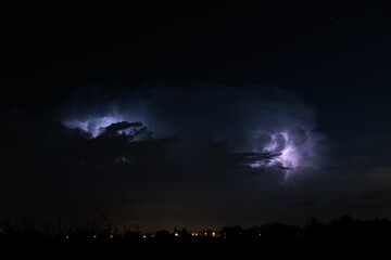 panoramica da lontano di un intenso temporale notturno, con fulmini visibile tra le nuvole, che passa sopra il nord est Italia