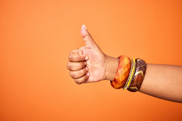 Hand, thumbs up and person with arm on orange background for thank you or confirm with gesture or...