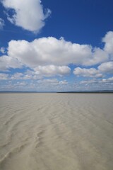 Fototapeta na wymiar Blick von Neusiedl am See im österreichischen Burgenland über das sedimenthaltige Wasser des Neusiedler Sees im Frühjahr. Über dem Wasser sind viele verschieden große Wolken zu sehen.