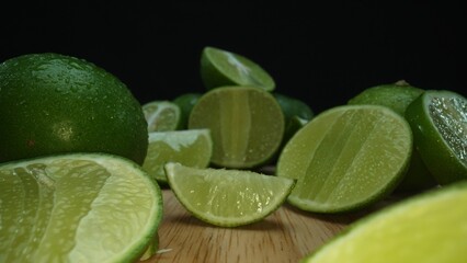 Close-up, a vibrant slice of fresh lime rests upon a rustic wooden cutting board, exuding freshness and vitality. The translucent membranes of the green lime slice placed on cutting board. Comestible.