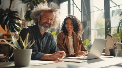 Two professionals in a modern office setting, a middle-aged Caucasian man with wild gray hair and a young African American woman with curly hair, smiling while discussing work at a bright, workspace - Powered by Adobe