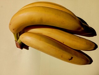 A bunch of yellow ripe bananas on a pale yellow background. Food and ingredients. Fruits and vegetables. Delicious juicy ripe bananas.