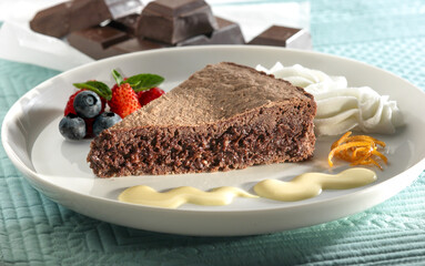 Chocolate cake with vanilla and cream sauce accompanied by strawberries and blueberries