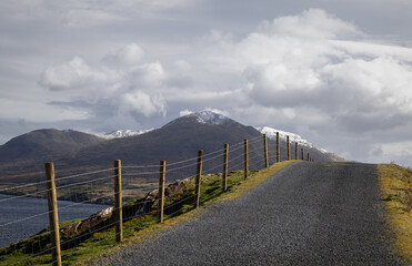 Country Road in Connemara, West of Ireland with snow capped mountains in the background