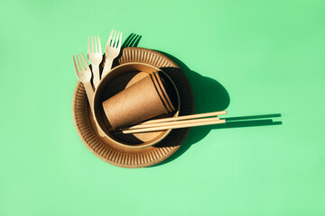 A set of paper utensils and wooden cutlery on a green background. Eco friendly, zero waste concept....