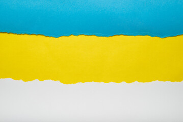 Torn pieces of blue and white paper on yellow background. Torn edges.