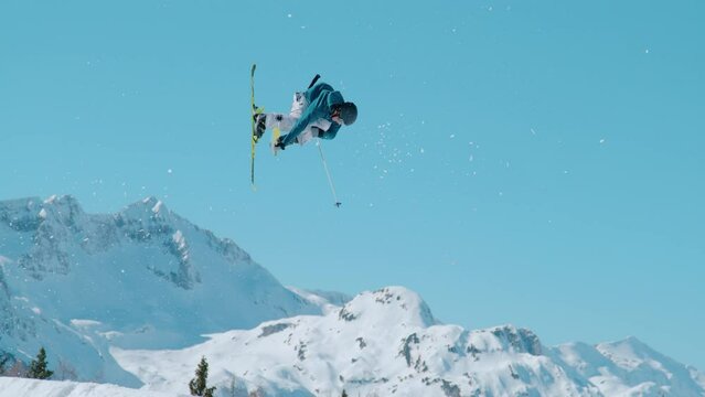VOGEL, BOHINJ, JULIAN ALPS, SLOVENIA, MARCH 2022: SLOW MOTION: Stunning view of freestyle skier doing trick while jumping kicker. Extreme athlete rotating through the air and performing grab trick.