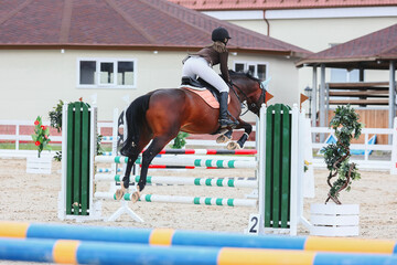 Rider jump to clear the green obstacle. Equestrian Sports, Show Jumping. Chestnut horse on course