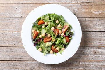 Healthy chickpea salad with tomato,lettuce and cucumber on wooden table. Top view