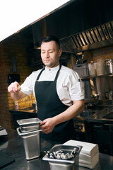 Caucasian chef holding tree branch while cooking dish at table in restaurant