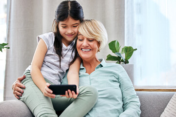 Grandmother, child and cellphone in home for online, development and happy together on couch. Girl,...