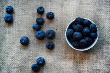 Blueberries in a white bowl on a burlap tablecloth. Juicy blueberries.