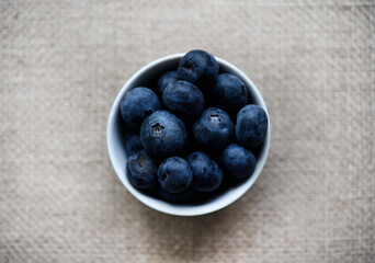 Blueberries in a white bowl on a burlap tablecloth. Juicy blueberries.