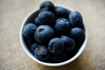 Blueberries in a white bowl on a burlap tablecloth. Juicy blueberries.