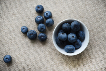Blueberries in a white bowl on a burlap tablecloth. Juicy blueberries.