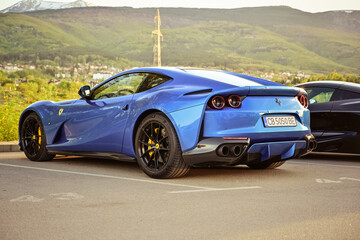 Obraz premium Italy- May 2024 Ferrari Blue car parked near a mountain. luxury sport Italian car