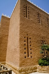 Low angle view on ancient clay walls of arabic tower in heritage village under clear sky