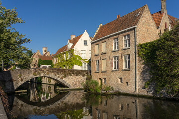 Peerden bridge and historic buildings reflected on the canal in the old town of the beautiful city of Bruges in Belgium in a sunny day.