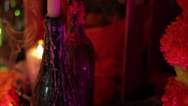 Dripping candles and incense smoke on Day of the Dead altar, offerings