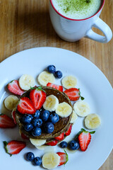 Green tea matcha latte and pancakes made with roll oats, soy milk, banana topping with fresh fruit 