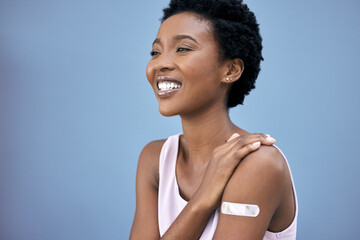 Black woman, proud and vaccine plaster in studio for prevention, happy and booster shot on blue background. Medication, smile and female person with pride for promote wellness, healthcare or medicine