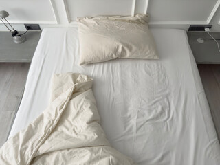 untidy bed with pillow and quilt in bedroom, hotel room interior