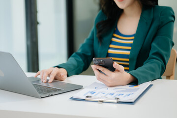 Business woman sitting front tablet ,laptop computer with financial graphs and statistics. at office.