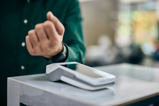 Focus on the man using his smartwatch to pay something, leaning to the payment machine.
