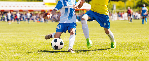 Young boys playing soccer game. Kids having fun in sport. Happy kids compete in football game. Running soccer players. Competition between players running and kicking football ball. Football school