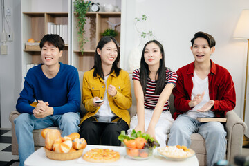 Young Asian friend having, enjoy evening party together at home. Attractive young man and woman having fun, eating food, celebrate at home