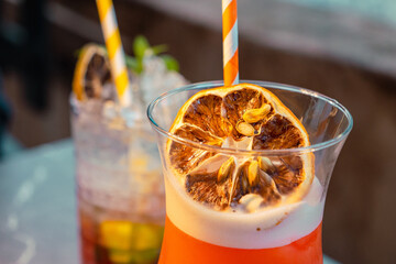 Gros plan d'un cocktail avec glaçons, orange et paille jaune 3