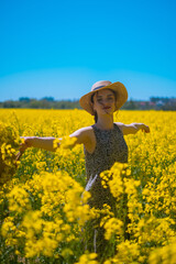 Woman twirls in dress amid blooming yellow rapeseed field, holding bag, perfect for festival or holiday-themed events.