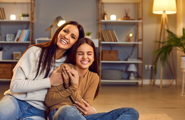 Mother and daughter share laughter, affection and tender moment, embracing on the floor at home...