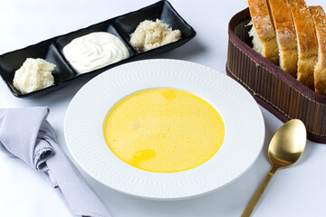 Traditional Romanian soup called ciorba de burta, served with fresh cream, garlic paste and bread. 