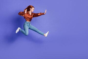 Full size profile photo of pretty young woman jump fight empty space wear brown shirt isolated on...