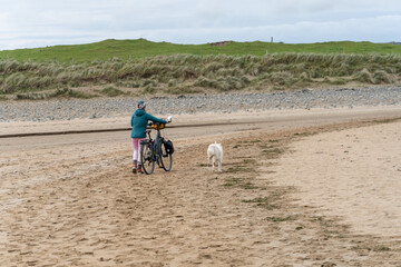 Cyclist woman and her dog on the beach