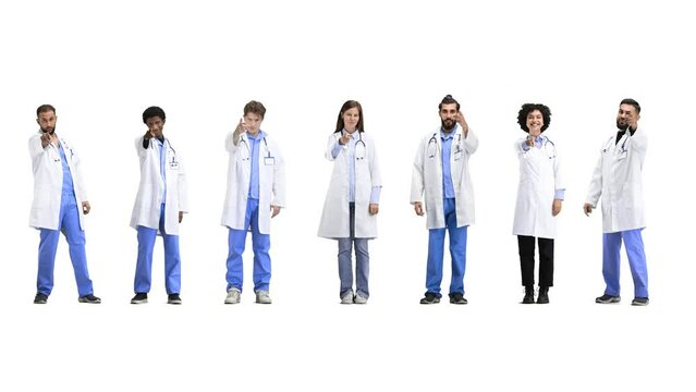 A group of doctors, in full height, on a white background, points forward