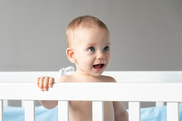 Close-up of a baby's face looking out of a crib with interest