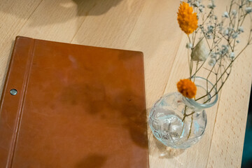 Carte de restaurant en cuir avec pot de fleur séché orange