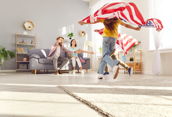 Happy funny children boy and girl having fun and running with flags of united states in living room...