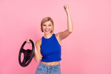 Portrait of nice girl hold wheel raise fist wear blue top isolated on pink color background