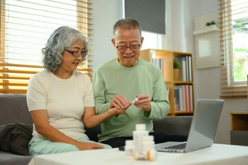 Senior husband helping his wife checking blood sugar level with glucometer at home. Health care...