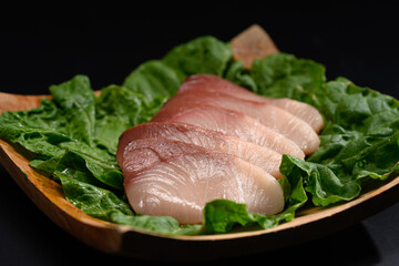Close up of fresh raw Hamachi sashimi on black plate. Japanese food style