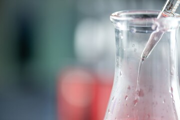 Close-up of a chemistry experiment with a pipette and a beaker of liquid