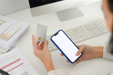 Close up view of businesswoman hand holding credit card and smartphone with blank display