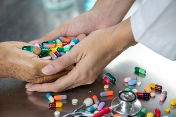 A doctor's hand holding a patient's hand with a lot of pills in it.