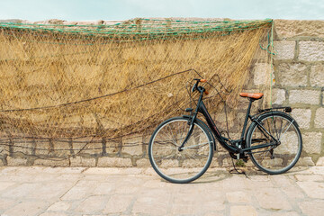 Vélo posé contre un mur avec filet de pêche - obrazy, fototapety, plakaty